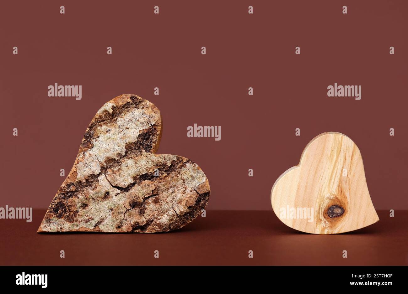 Holzherzen mit Rinde und ohne Rinde vor rotem Hintergrund Stockfoto