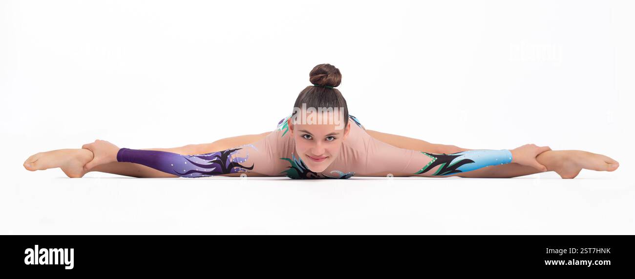 Junge akrobatische Turnerin bei Gymnastikübungen. Sich auf dem Boden ausstrecken. Isoliert auf weißem Hintergrund. Sport, Wettbewerb und gesundes Leben Stockfoto