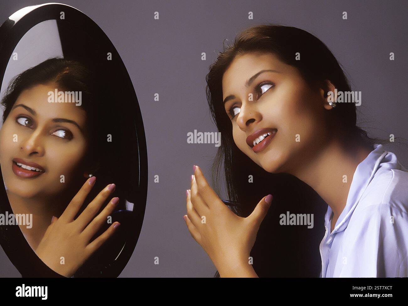 Südasiatische Indianerin kämmt ihre Haare mit Kamm vor einem Spiegel Stockfoto