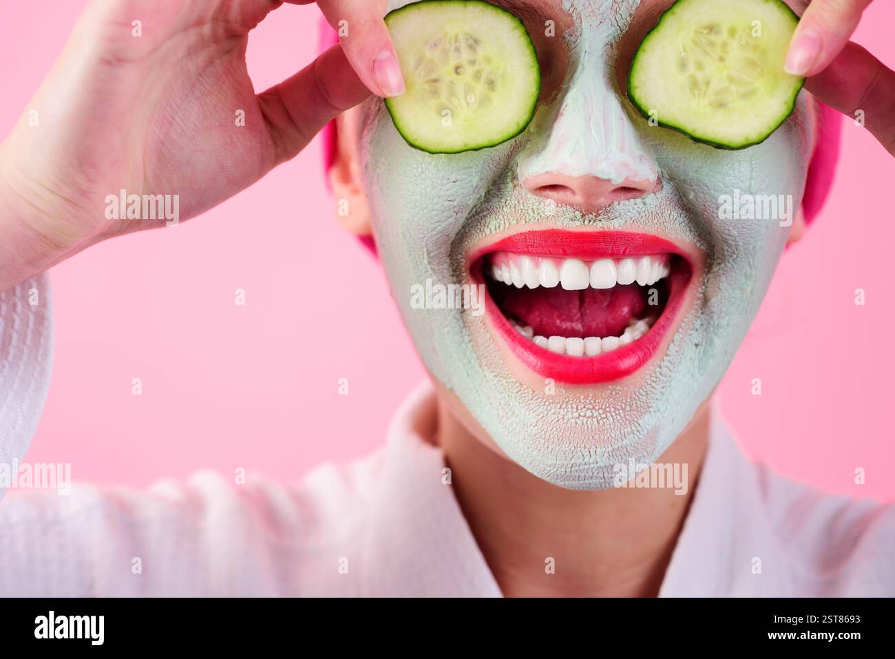Nahaufnahme-Porträt einer Frau mit tonkosmetischer Gesichtsmaske und frischen Gurkenscheiben auf den Augen. Beauty, Hautpflege und kosmetische Verfahren. Lächelndes Mädchen mit Stockfoto