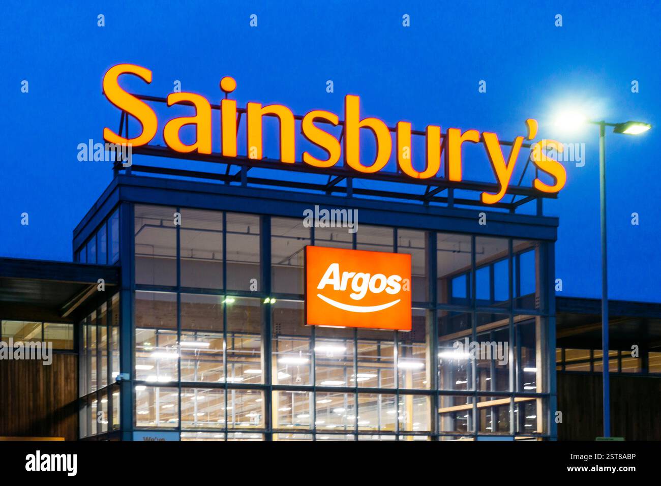 Sainsbury's Supermarkt in der Abenddämmerung mit Schild für den Argos-Laden in King's Lynn, Norfolk. Stockfoto