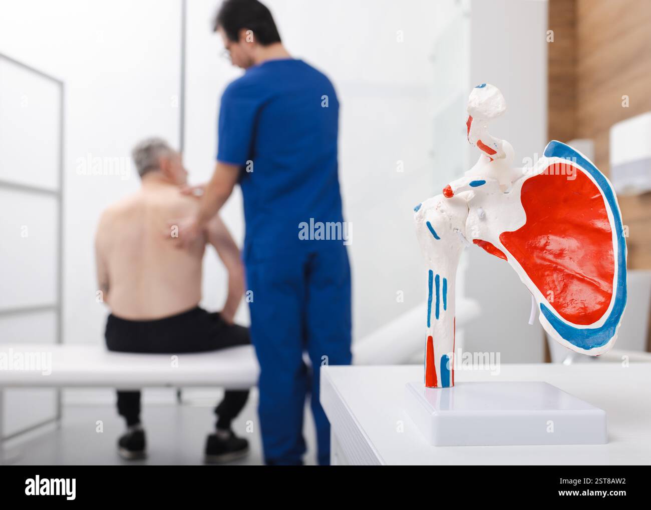 Traumatologe bietet Untersuchung für ältere Patienten in der Klinik, Schwerpunkt auf Schultergesundheit mit medizinischem Modell im Vordergrund. Die menschliche Schulterluxation Stockfoto