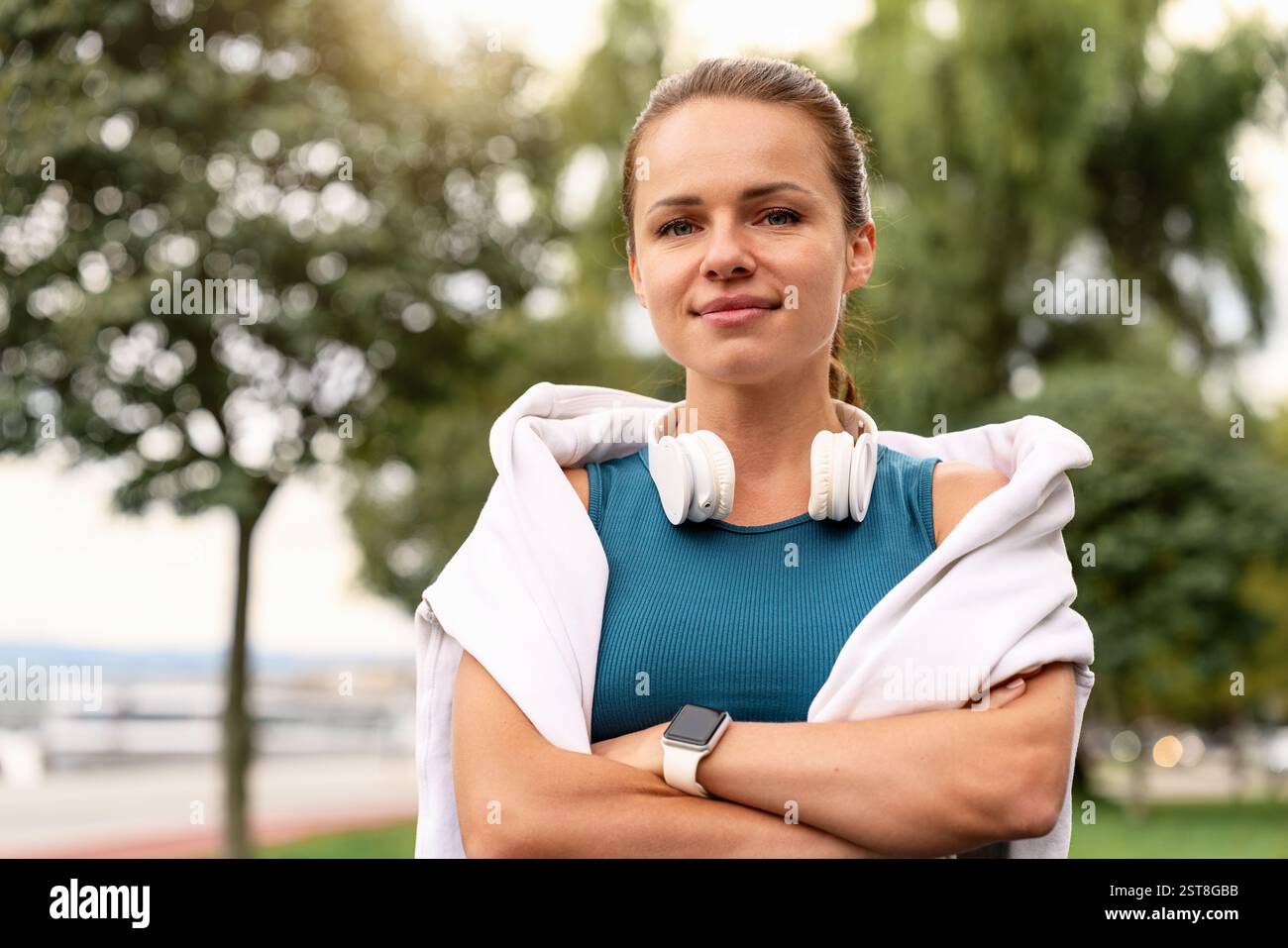 Porträt einer jungen Frau mit Kopfhörern um den Hals, die draußen laufen Stockfoto