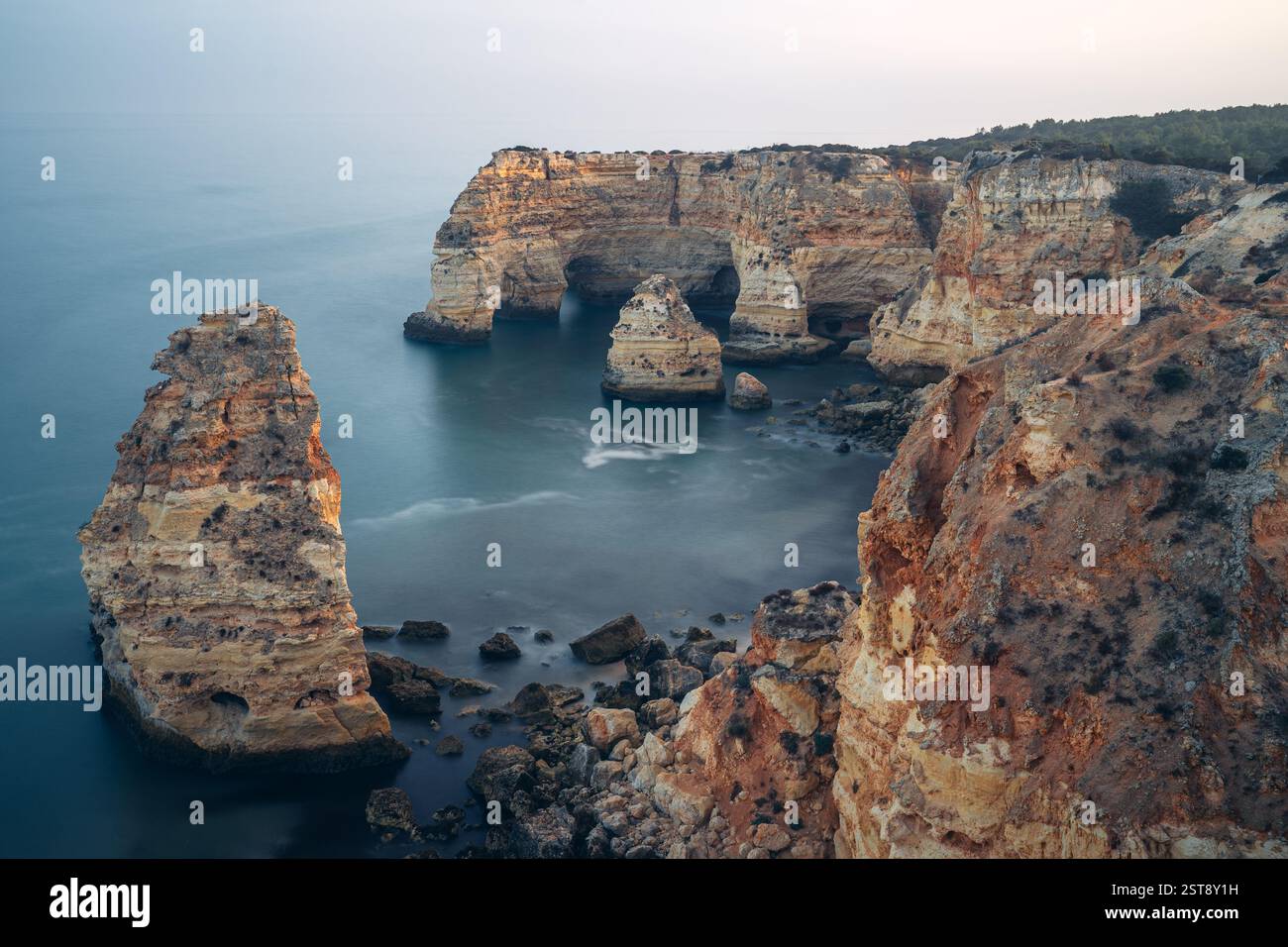 Klippen, Felsformationen und Naturbögen am Strand La Marina bei Sonnenuntergang in der Algarve in der Nähe der Städte Albufeira und Portimao. Portugal. Stockfoto