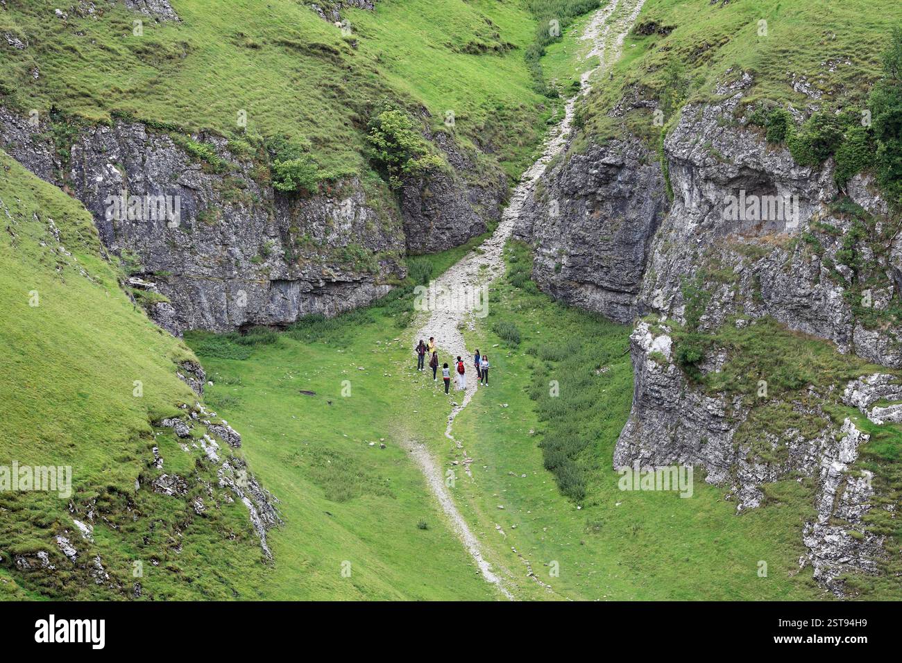 Junge Leute erkunden Cave Dale, ein trockenes Karsttal (aus karboniferem Kalkstein) im Peak District National Park, nahe Castleton, Derbyshire. Stockfoto