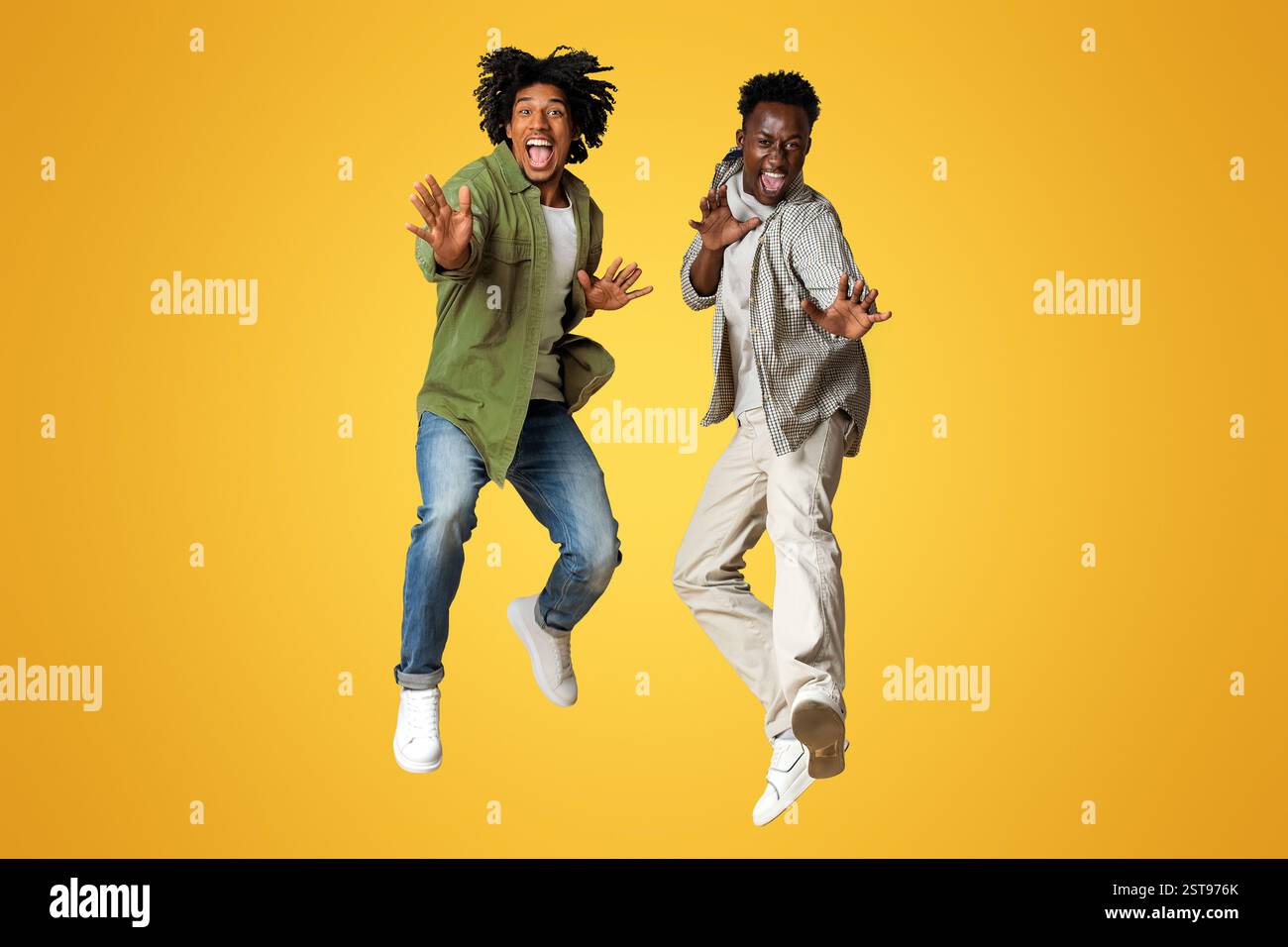 Zwei Fröhliche, Emotionale Afroamerikanische Jungs Springen Über Beigen Studiohintergrund Stockfoto