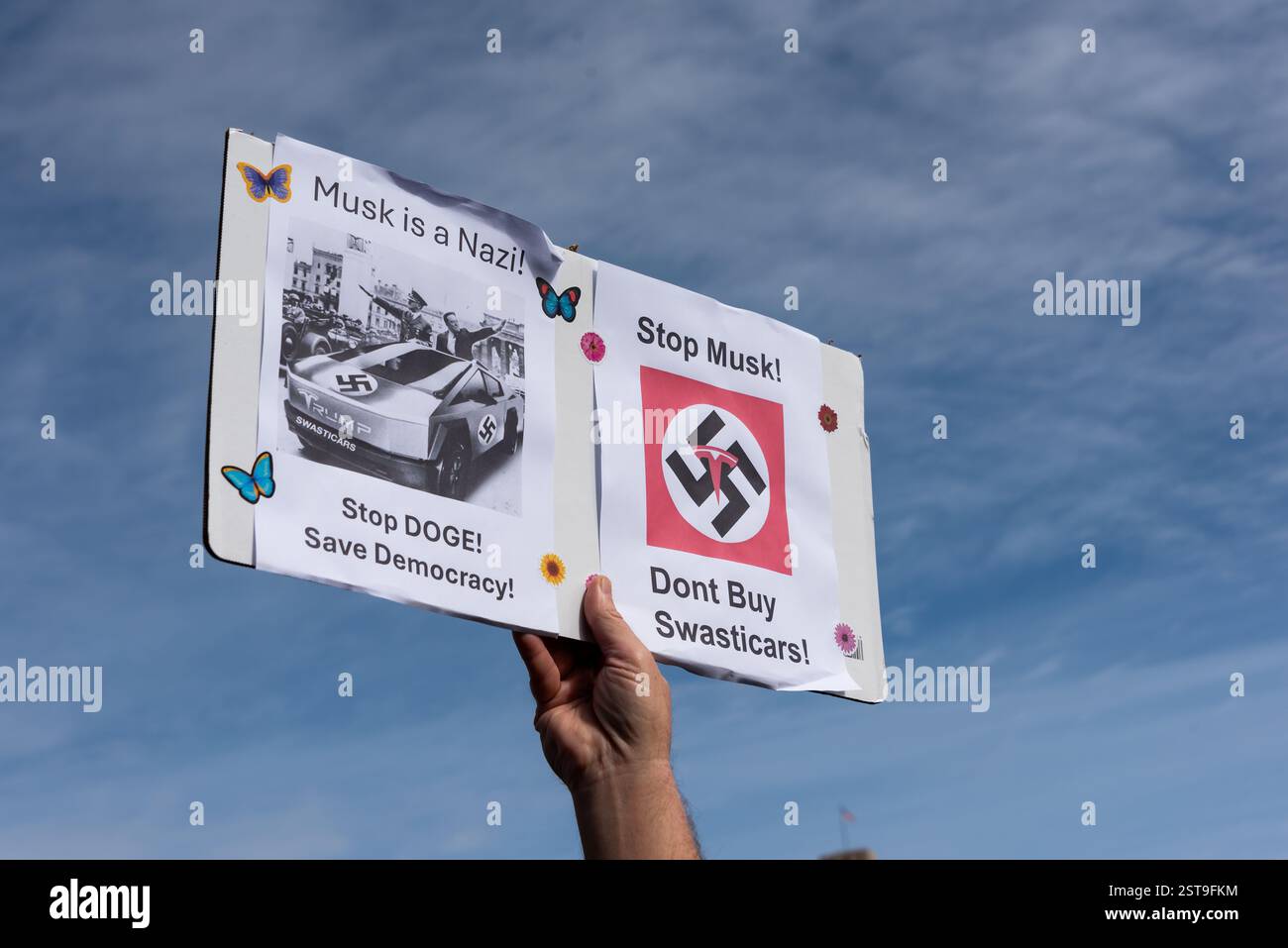 San Francisco, Kalifornien, USA, 17. Februar 2025. Während des Protestes des Präsidenten vor dem Rathaus in San Francisco wird ein Schild mit der Aufschrift „Musk is a Nazi! Halten Sie DEN HUND auf! Rettet Die Demokratie!“ Und „Halt Musk auf! Kaufen Sie keine Swasticars!“ Mit Bildern eines Tesla-Fahrzeugs und Tesla-Logo kombiniert mit Hakenkreuzen. Shelly Rivoli/Alamy Stockfoto