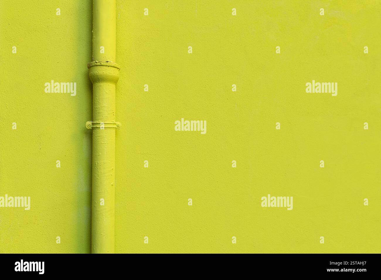 Gelbe Wandstruktur und eine gelbe fallrinne eines Hauses. Foto geeignet für Hintergrund oder Design Hintergrund. Kopierraum für Grafikdesign. Stockfoto