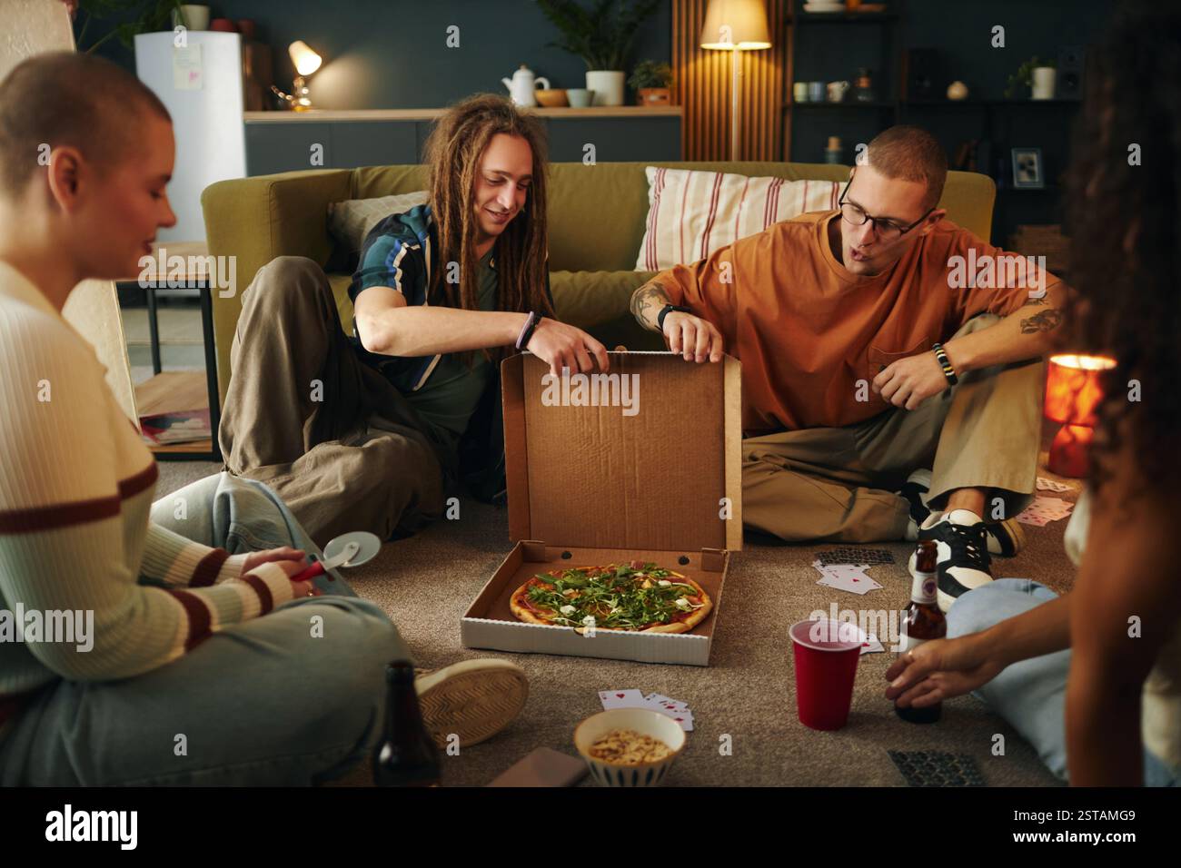 Genießen Sie Pizza mit Freunden in gemütlichem Wohnzimmer Stockfoto