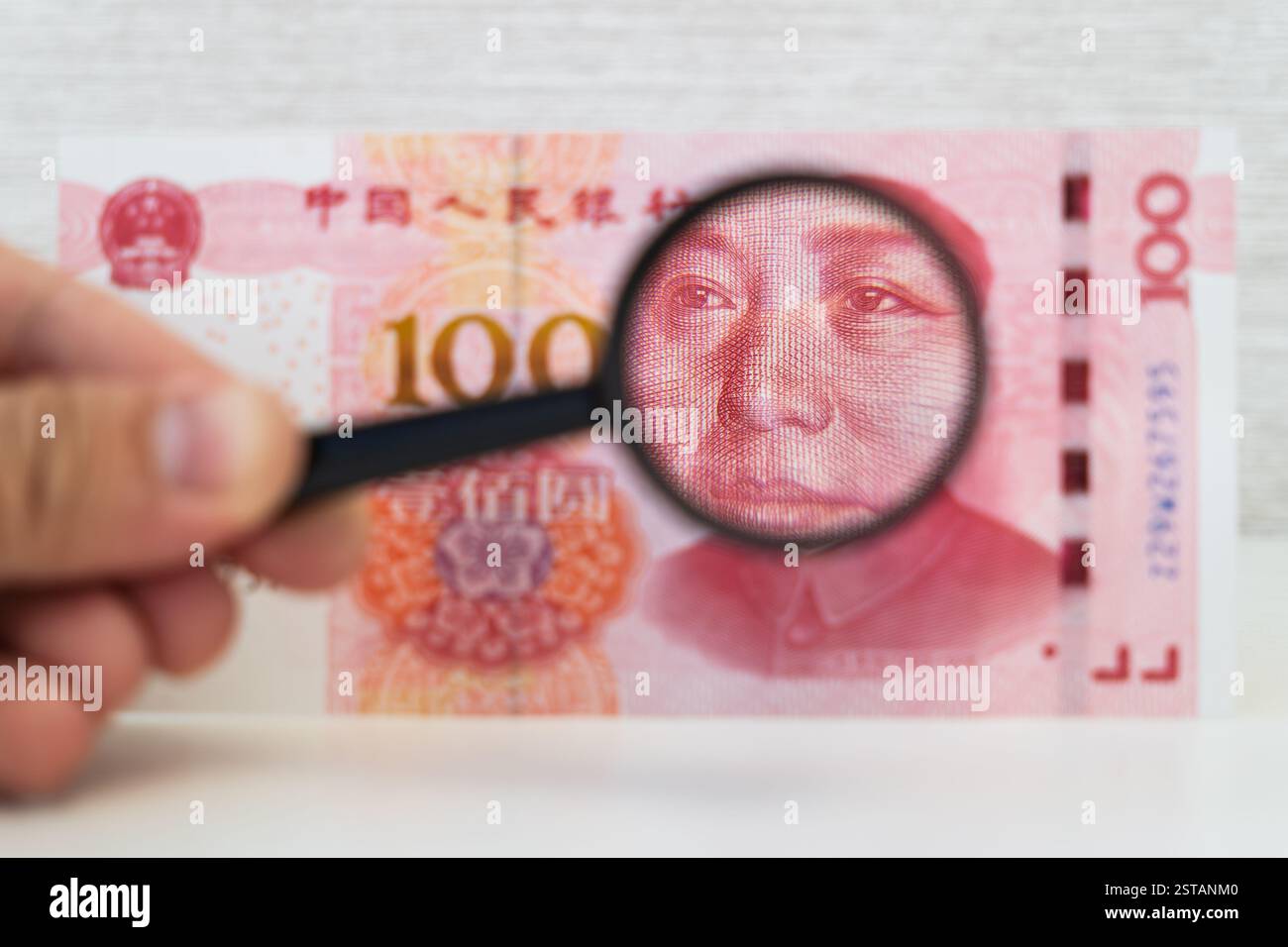 100-Dollar-Schein und Lupe auf Weiß. Die Hände der Männer halten Dollar und Lupe. Überprüfung der Echtheit des amerikanischen Banknot Stockfoto