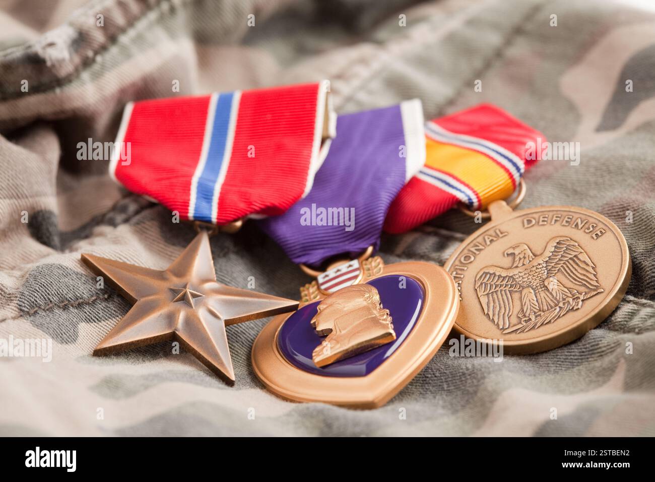 Bronze-, Purple Heart- und National Defense-Medaillen auf Camouflage-Material. Stockfoto