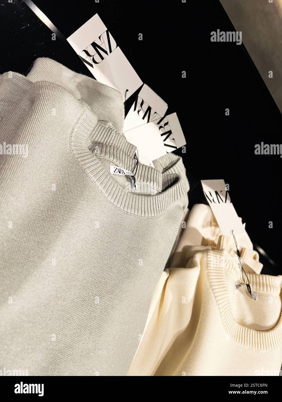 Lemberg, Ukraine - 16. Februar 2025: Elegante Pullover mit Zara-Markenetiketten in Nahaufnahme auf schwarzer Oberfläche. Stockfoto