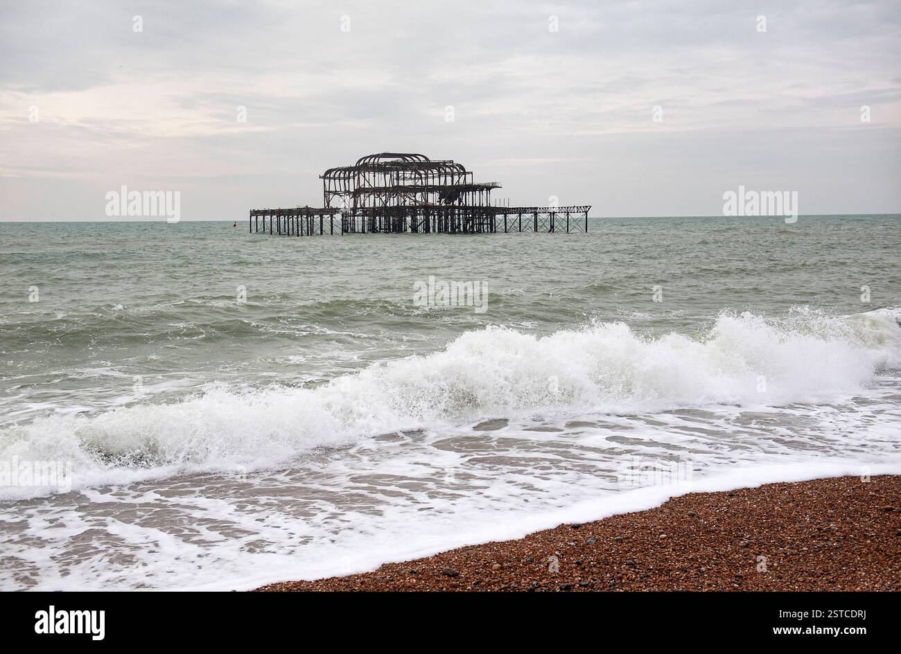 Brighton East Sussex England Vereinigtes Königreich Februar 2025 Wellen stürzen auf den Kieselstrand vor den skelettierten, baufälligen Ruinen des alten West Pier. Brighton ist vielleicht einer der bekanntesten englischen Badeorte an der Südküste am Ärmelkanal. Stockfoto