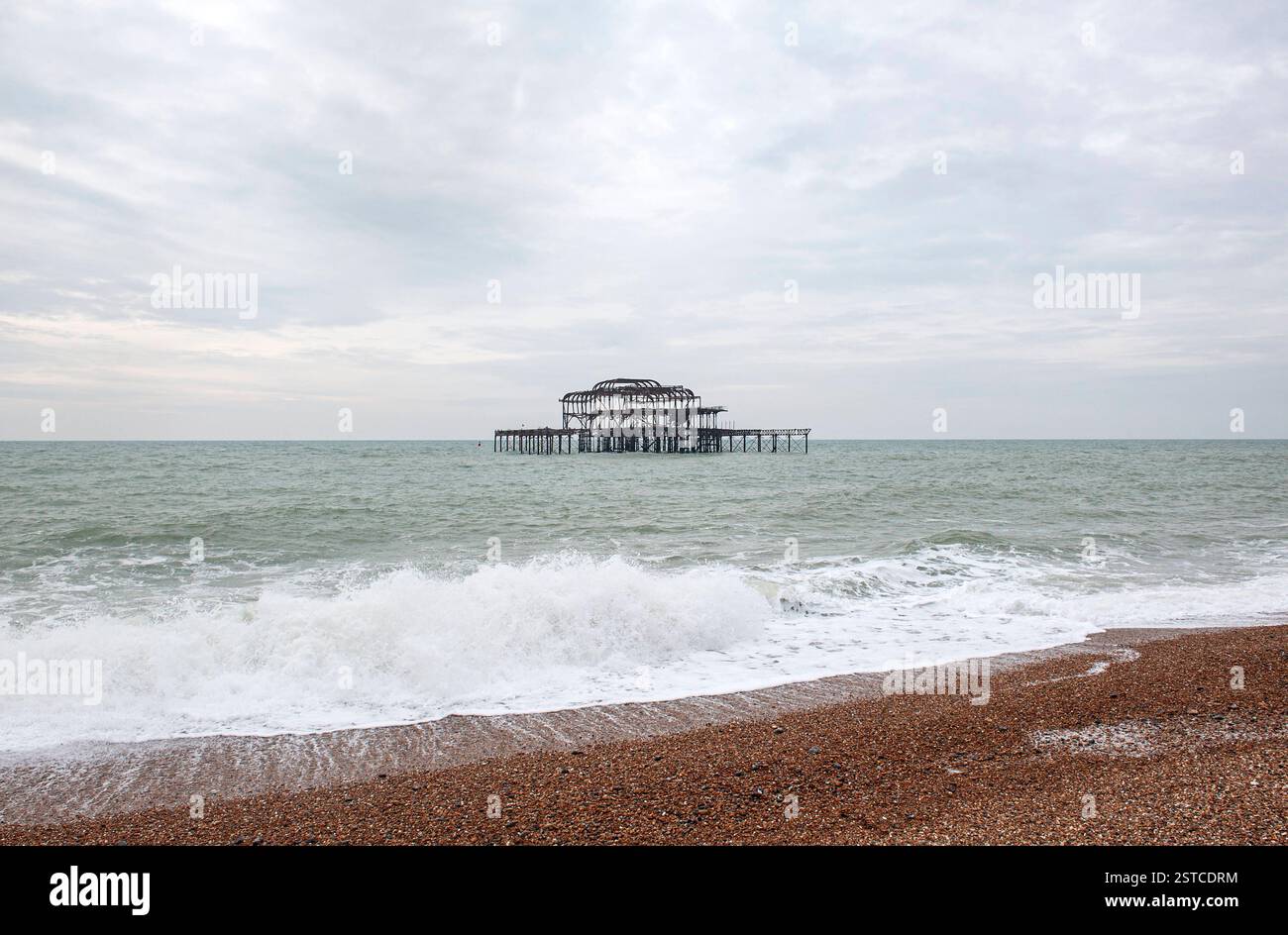 Brighton East Sussex England Vereinigtes Königreich Februar 2025 Wellen stürzen auf den Kieselstrand vor den skelettierten, baufälligen Ruinen des alten West Pier. Brighton ist vielleicht einer der bekanntesten englischen Badeorte an der Südküste am Ärmelkanal. Stockfoto