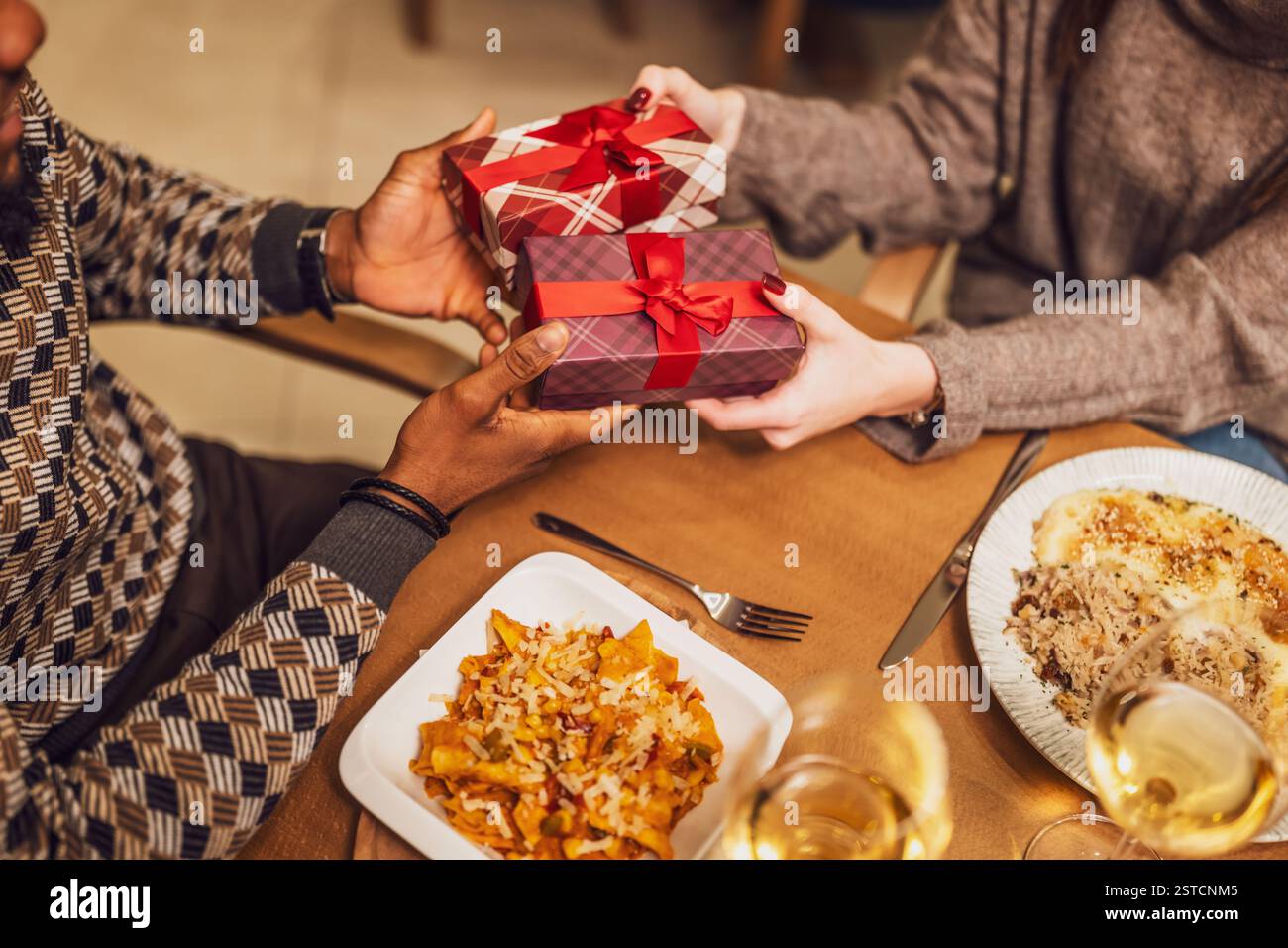 Nahaufnahme von zwei Personen, die beim Abendessen im Restaurant Geschenke austauschen. Stockfoto