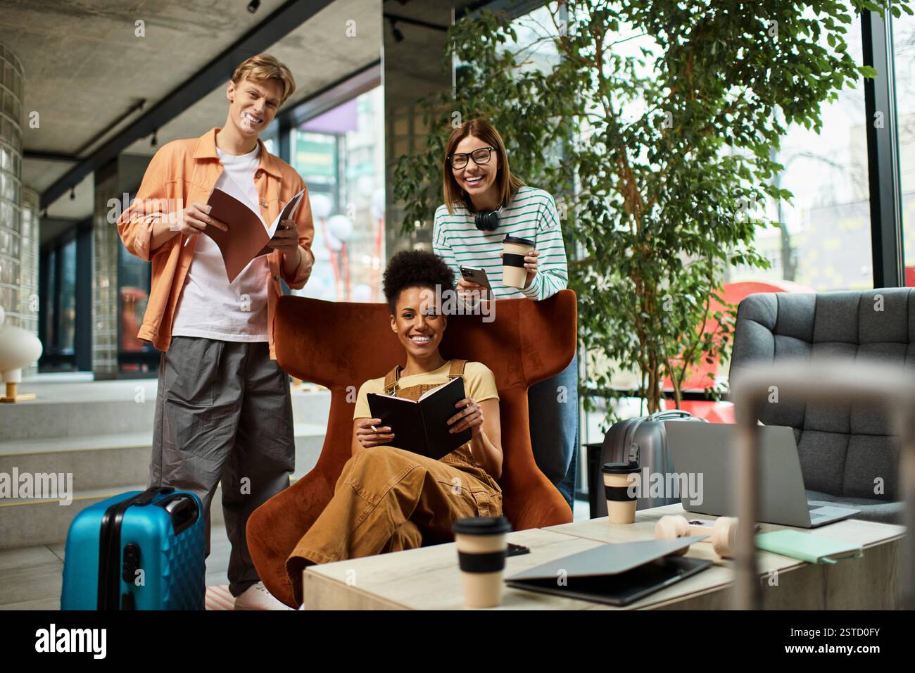 Drei Kollegen unterhalten sich in der Lobby des Hotels, tauschen Ideen aus und lachen, während sie sich entspannen. Stockfoto