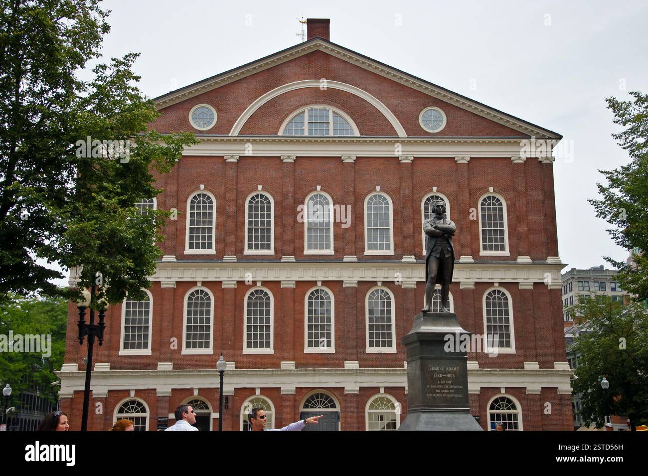 Der Faneuil Hall Marketplace ist ein historisches Wahrzeichen von Boston. Das Backsteingebäude mit Bogenfenstern und Uhrenturm ist voller Aktivität, während die Menschen sich aufhalten Stockfoto