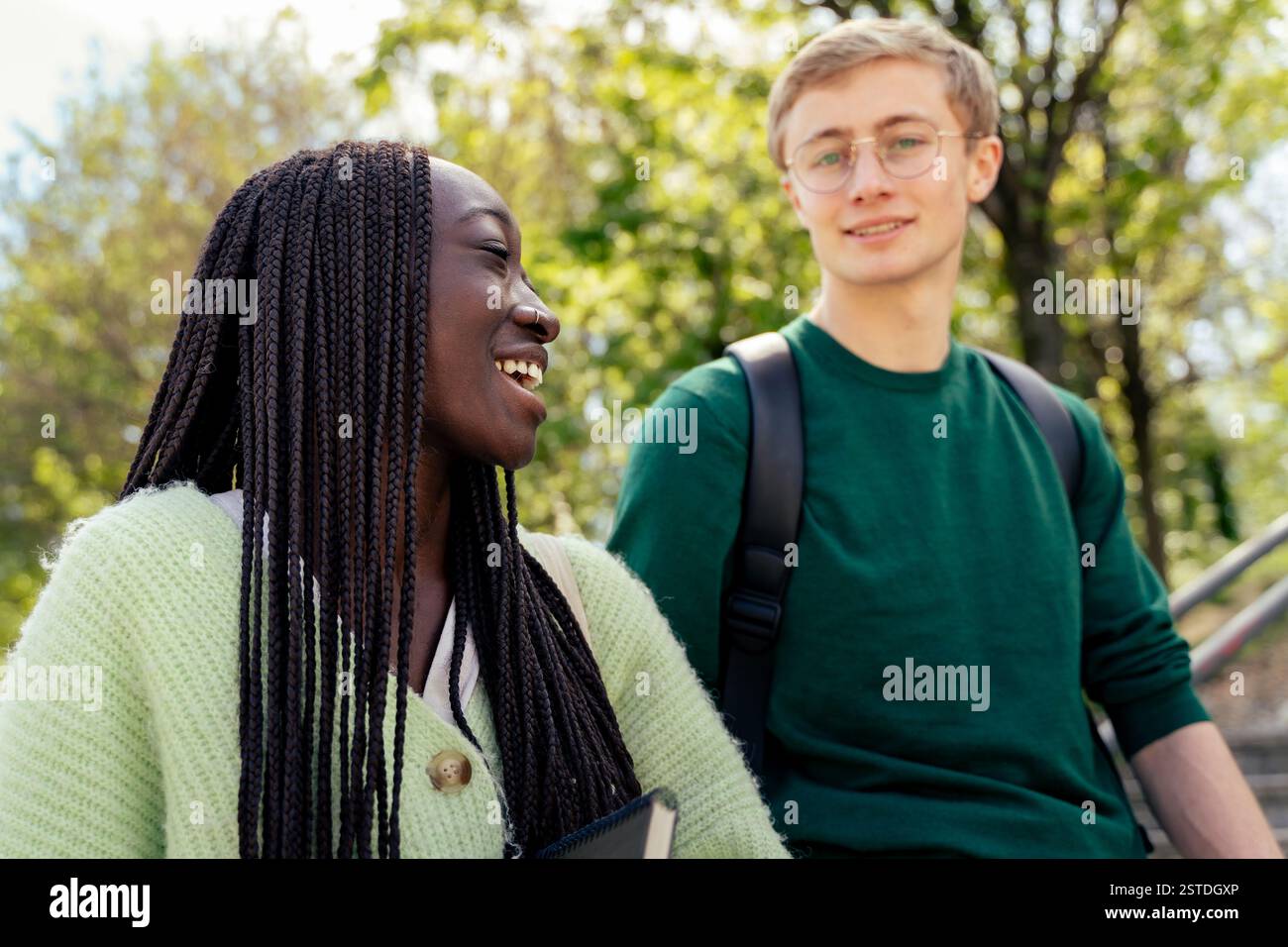 Zwei Studenten, die einen freudigen Moment auf einem grünen Universitätscampus verbringen. Eine großartige Darstellung der Freundschaften und des Wohlbefindens der Schüler im akademischen Leben. Stockfoto