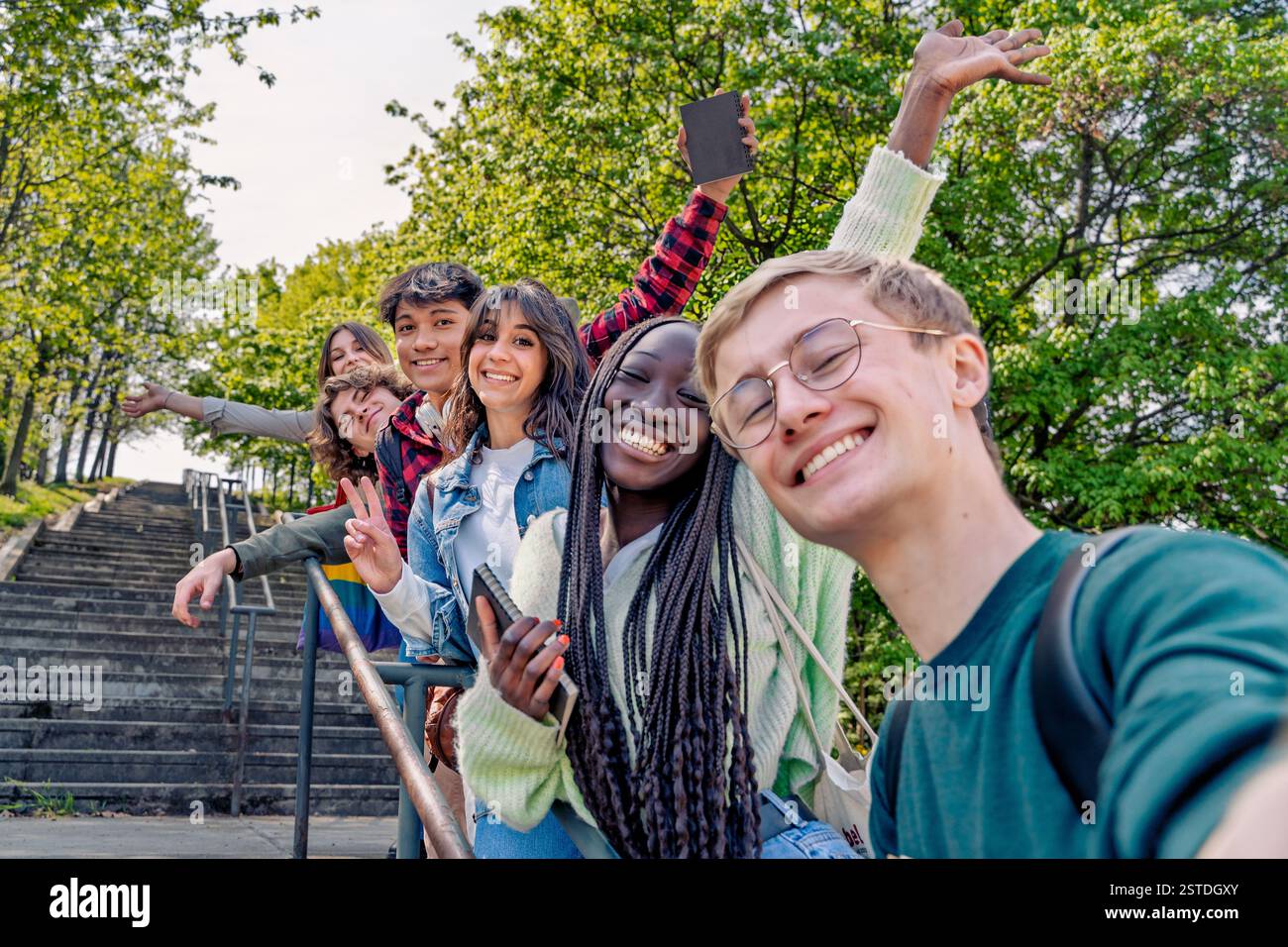 Eine vielfältige Gruppe von Schülern macht ein Selfie im Freien, lächelt und hat Spaß in einer natürlichen Umgebung. Stockfoto