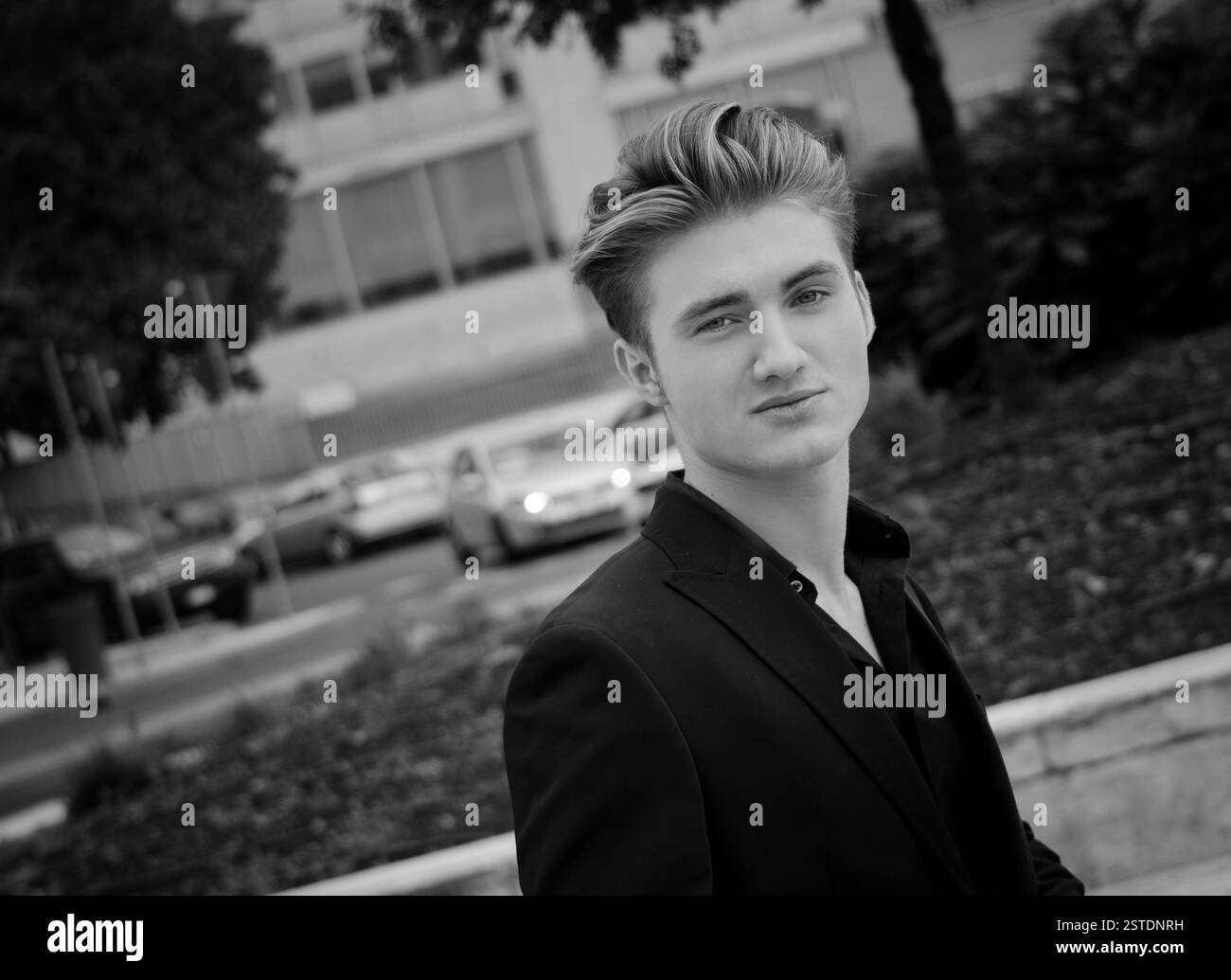 Attraktiver blauäugiger, blonder junger Mann draußen in der Stadt Stockfoto