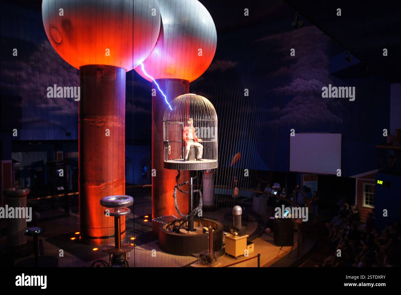 Museum of Science, Boston. Tesla-Spulenshow mit Blitzschlägen. Der Mann sitzt unverletzt in einem Faraday-Käfig. Elektrizitätsvorführung, Boston. Wissenschaft Stockfoto