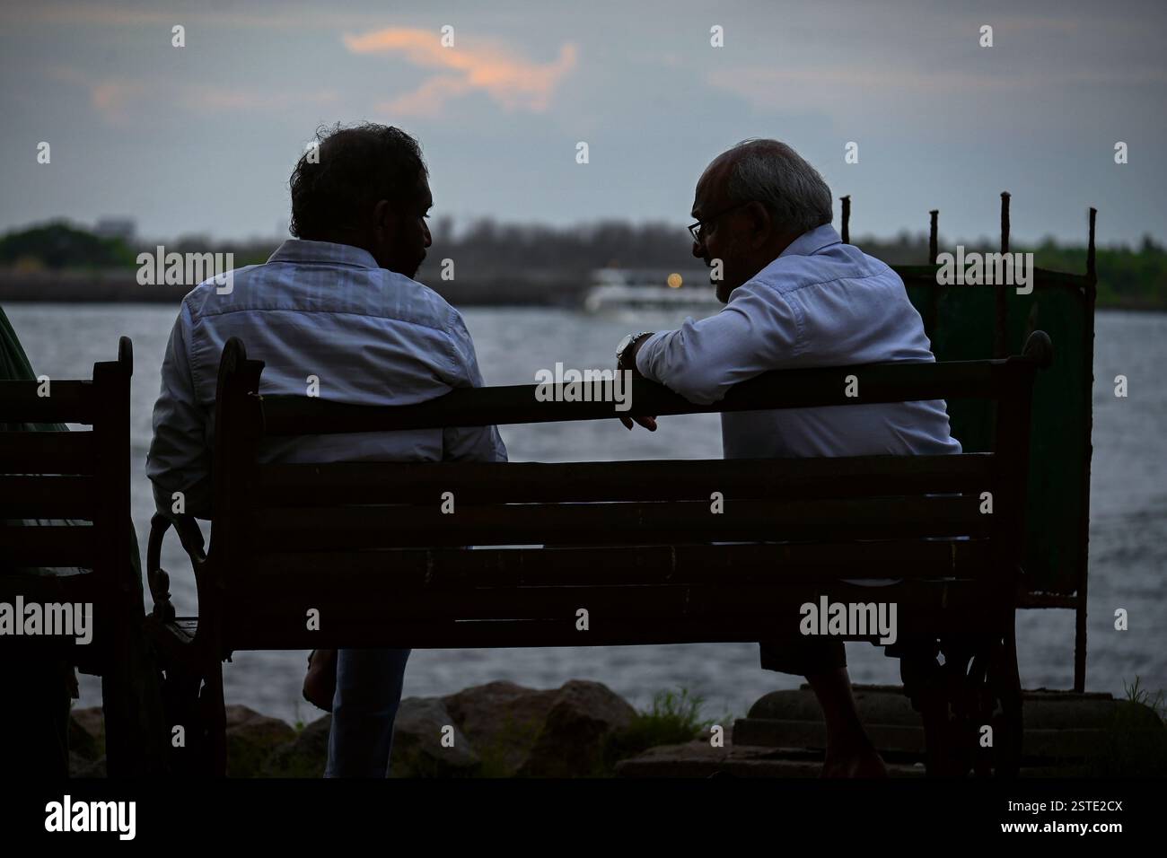 Zwei alte Freunde, eine Bank, das Meer und endlose Geschichten in der Abendbrise. Stockfoto