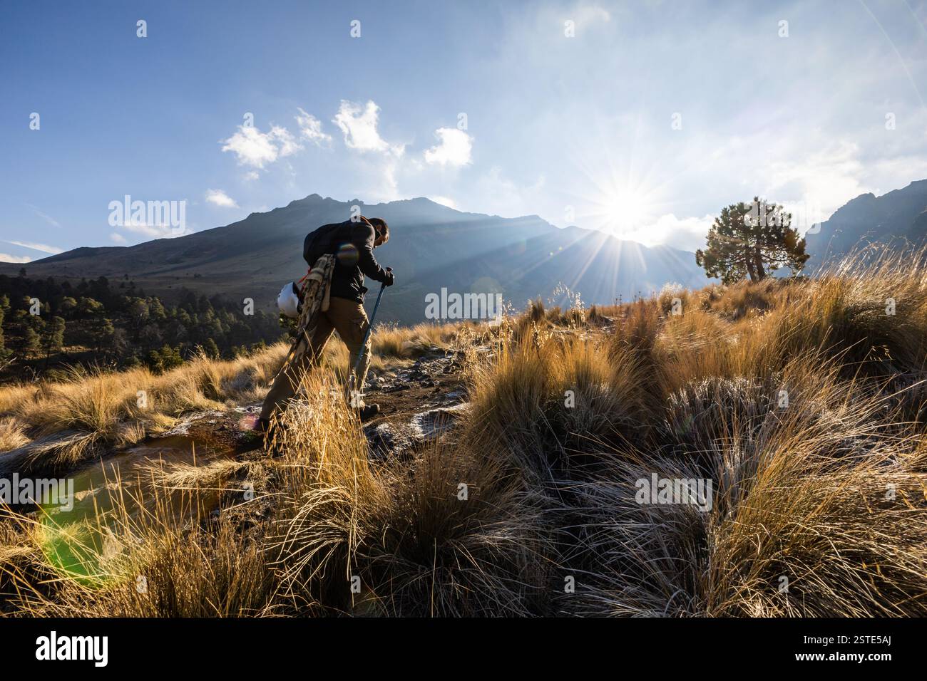 Ein einsamer Bergsteiger, der einen steilen Vulkan hinaufsteigt und den Geist des Abenteuers zeigt. Perfekt für Wanderungen, Trekking, Bergsteigen und Rucksacktouren. Stockfoto