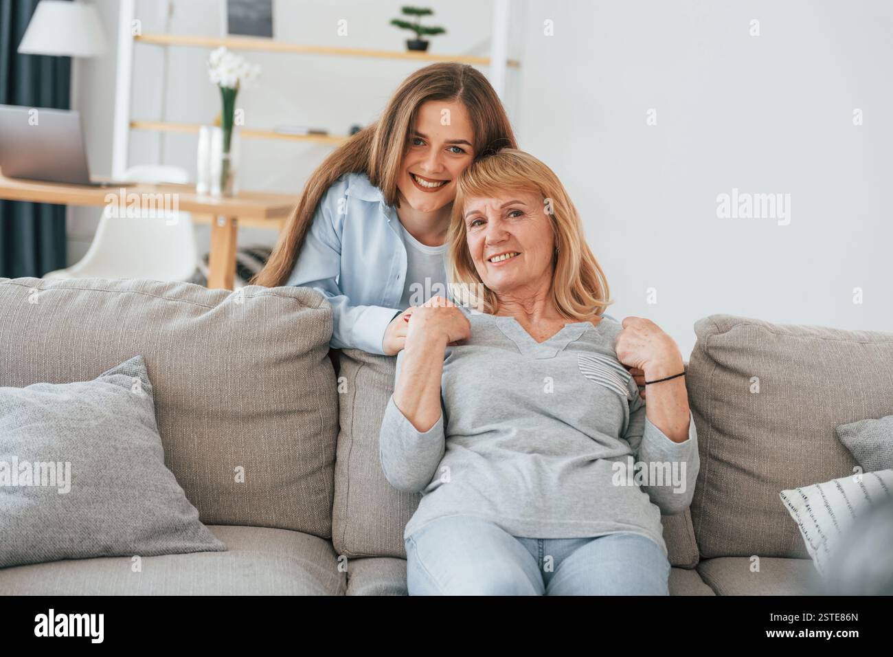 Lächelnd und in die Kamera schauend. Mutter und Tochter sind zu Hause zusammen. Stockfoto