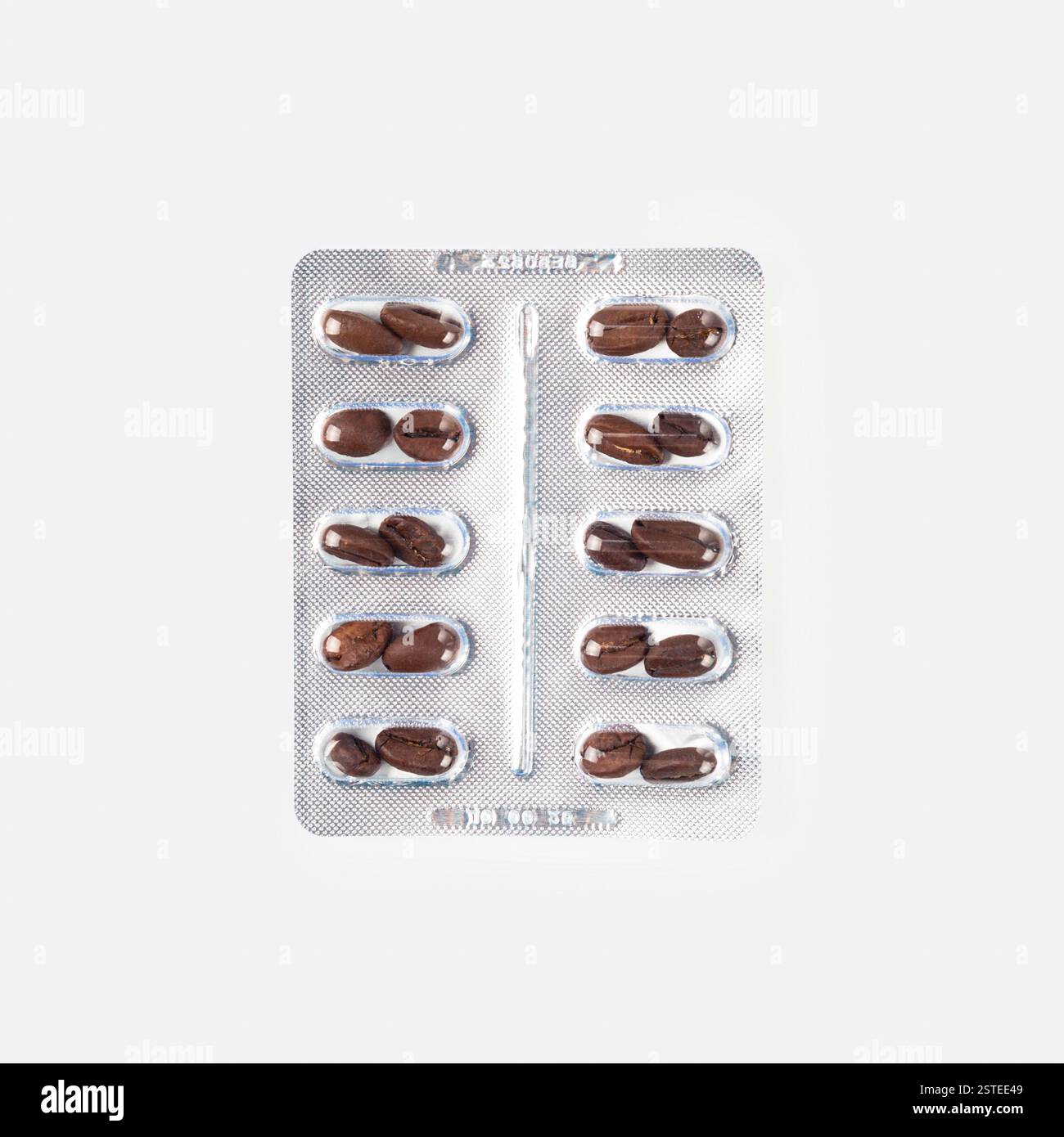 Blisterpackung mit Kaffeebohnenförmigen Pillen auf weißem Hintergrund, was auf ein medizinisches oder gesundheitsbezogenes Konzept hindeutet, das mit Koffein oder Energie-Boosting verbunden ist Stockfoto