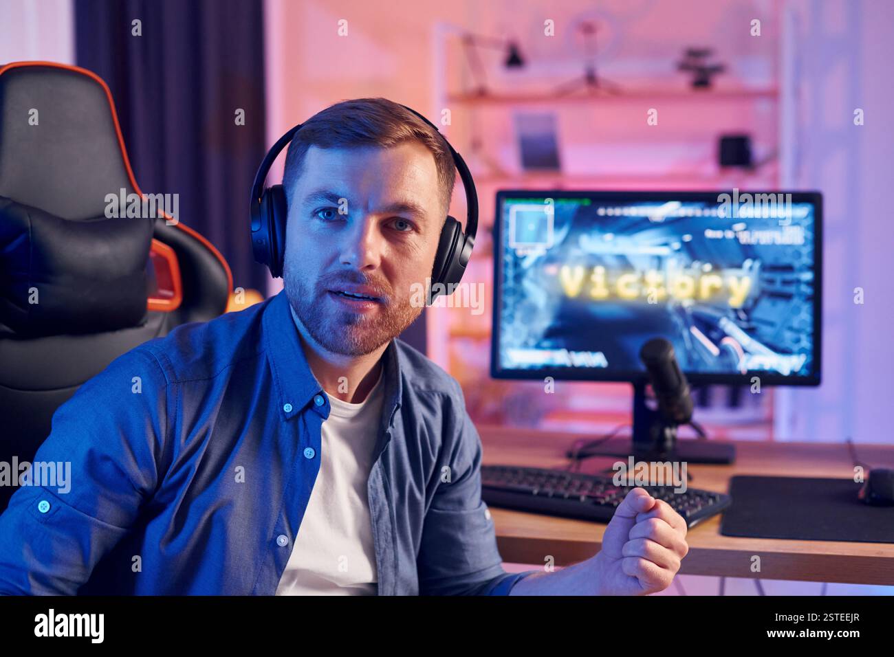 Der Mann gewinnt dieses Spiel. Online-Streamer spielt FPS-Shooter zu Hause. Stockfoto