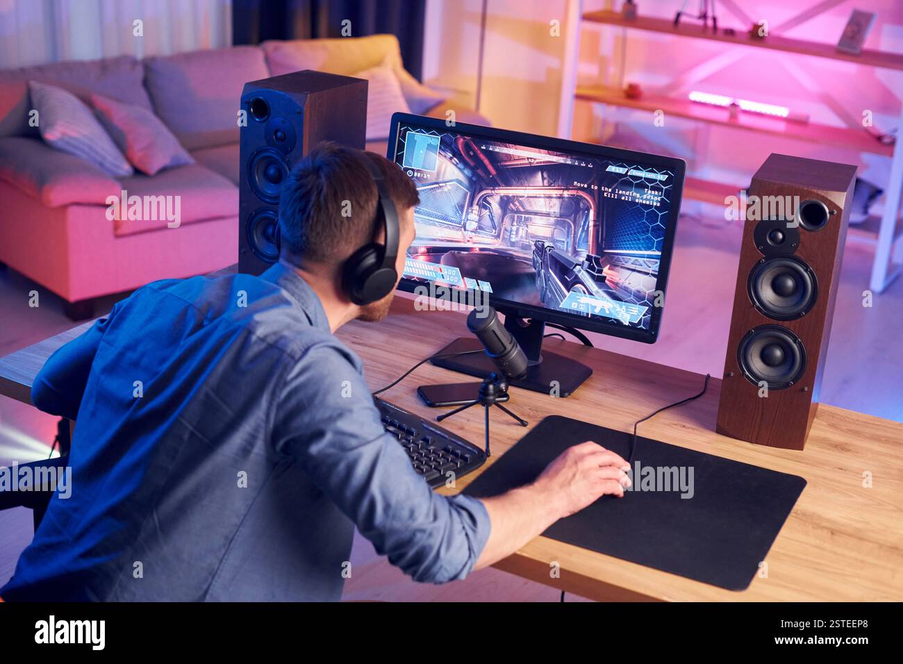 Konzentriert auf das Spielen. Man streamt FPS-Shooter-Spiel zu Hause. Stockfoto