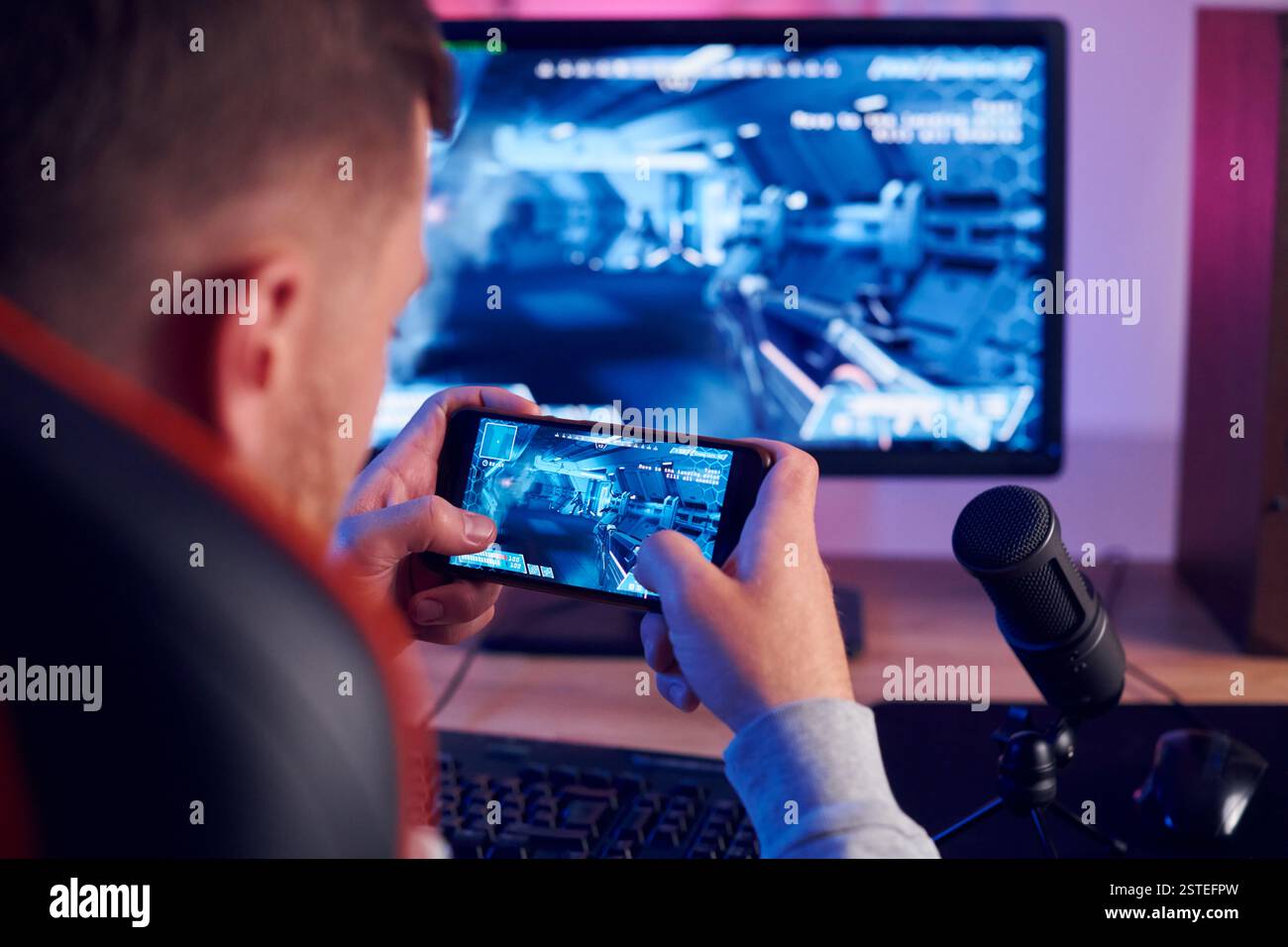 Smatphone halten und den Sieg feiern. Online-Streamer, der FPS-Shooter zu Hause spielt. Stockfoto