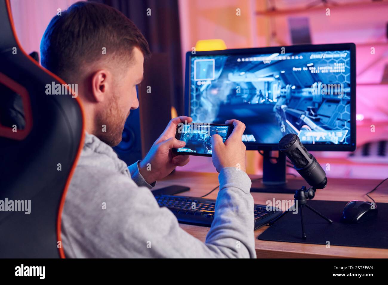 Smatphone halten und den Sieg feiern. Online-Streamer, der FPS-Shooter zu Hause spielt. Stockfoto