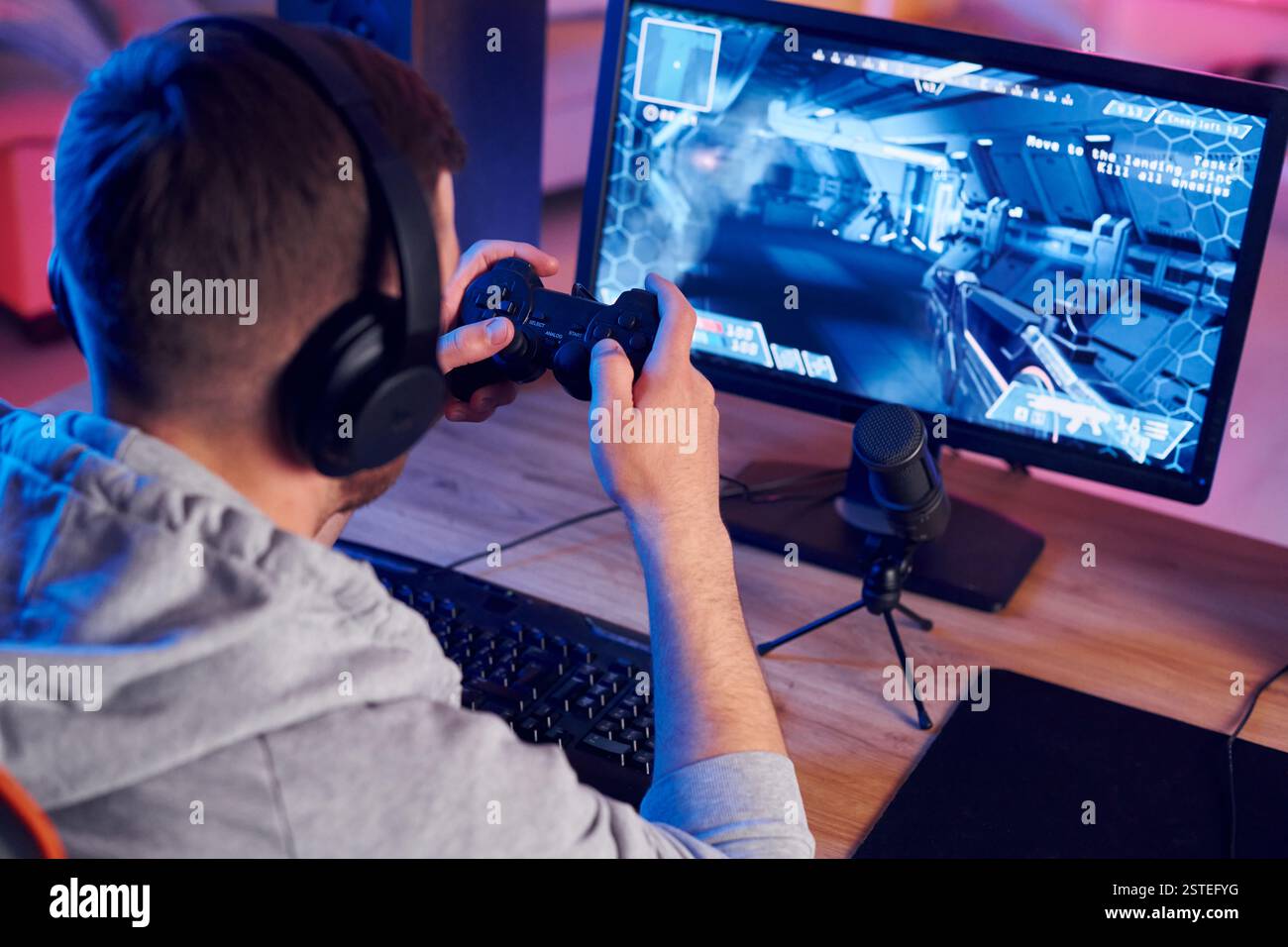 Mit dem Joystick. Online-Streamer, der FPS-Shooter zu Hause spielt. Stockfoto