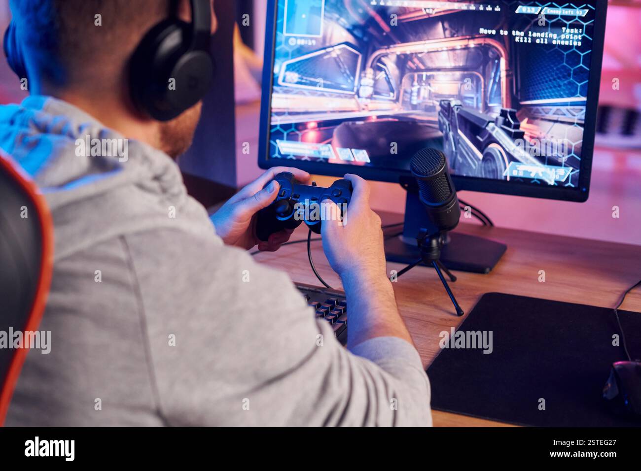 Mit dem Joystick. Online-Streamer, der FPS-Shooter zu Hause spielt. Stockfoto