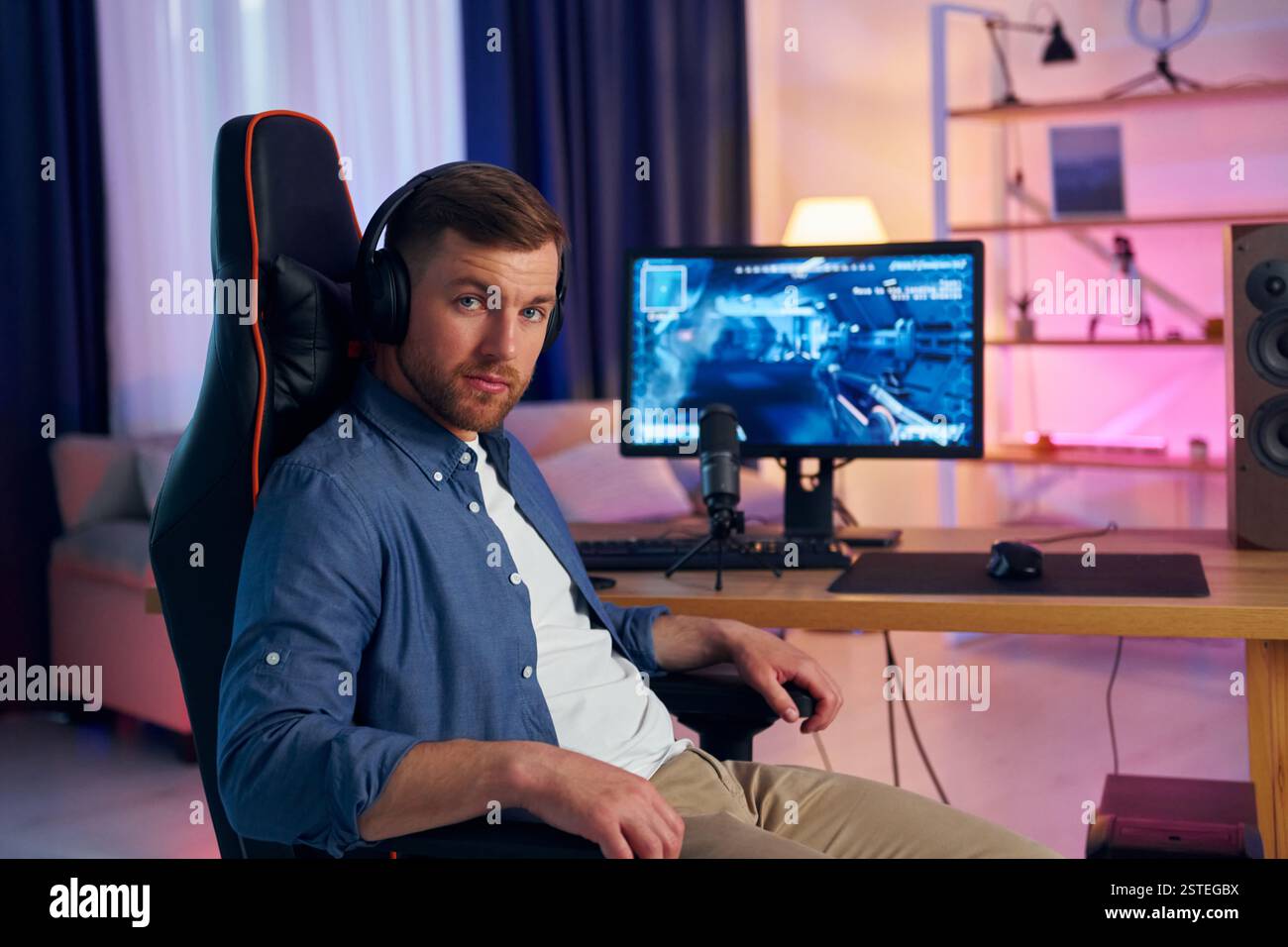 Auf dem Stuhl sitzen. Online-Streamer, der FPS-Shooter zu Hause spielt. Stockfoto