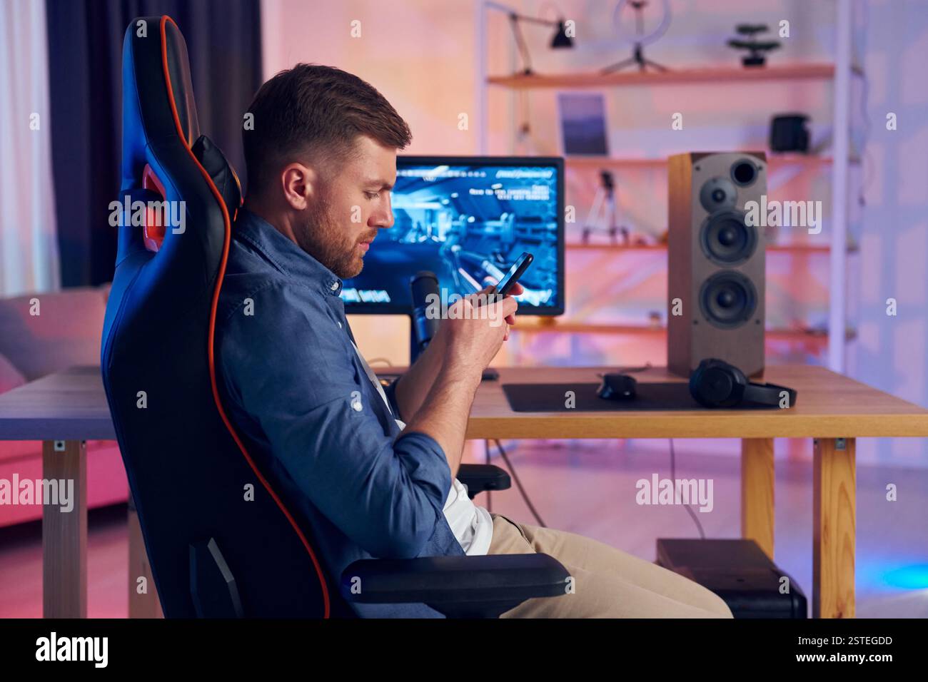 Auf dem Stuhl sitzen. Online-Streamer, der FPS-Shooter zu Hause spielt. Stockfoto