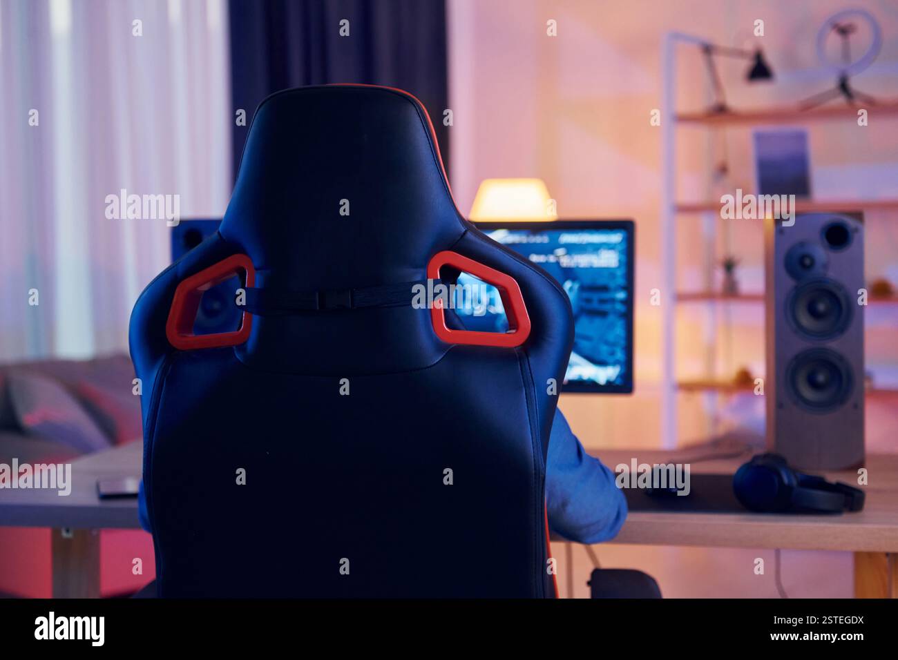 Auf dem Stuhl sitzen. Online-Streamer, der FPS-Shooter zu Hause spielt. Stockfoto