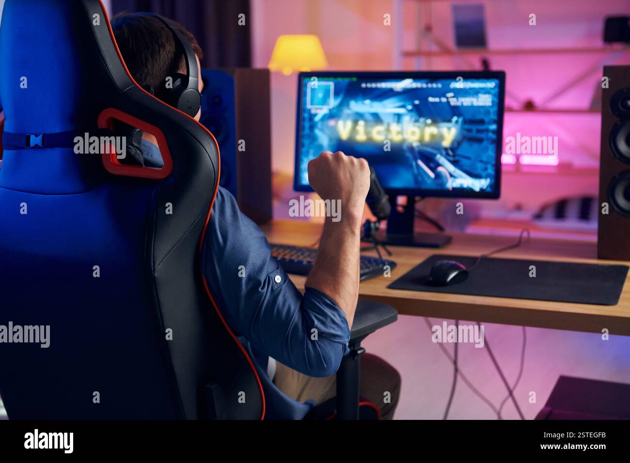Auf dem Stuhl sitzen. Online-Streamer, der FPS-Shooter zu Hause spielt. Stockfoto