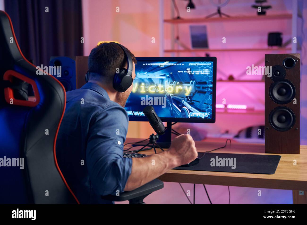 Blick von hinten. Online-Streamer, der FPS-Shooter zu Hause spielt. Stockfoto
