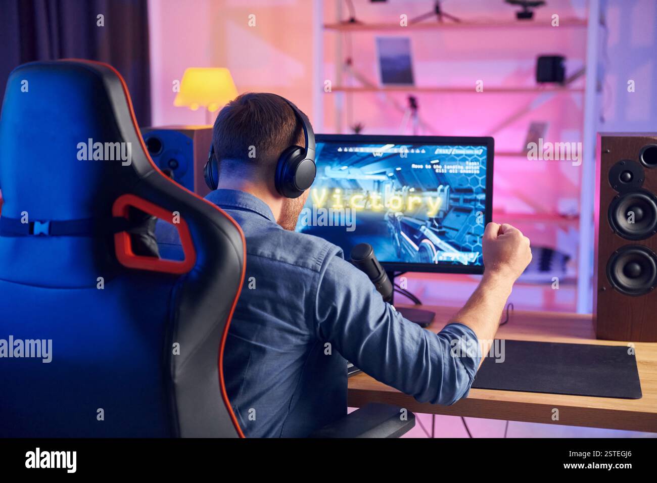 Blick von hinten. Online-Streamer, der FPS-Shooter zu Hause spielt. Stockfoto