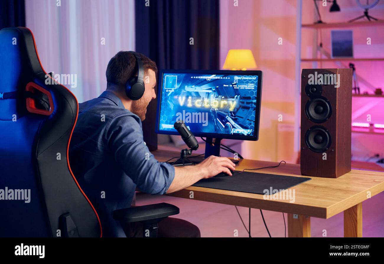 Blick von hinten. Online-Streamer, der FPS-Shooter zu Hause spielt. Stockfoto