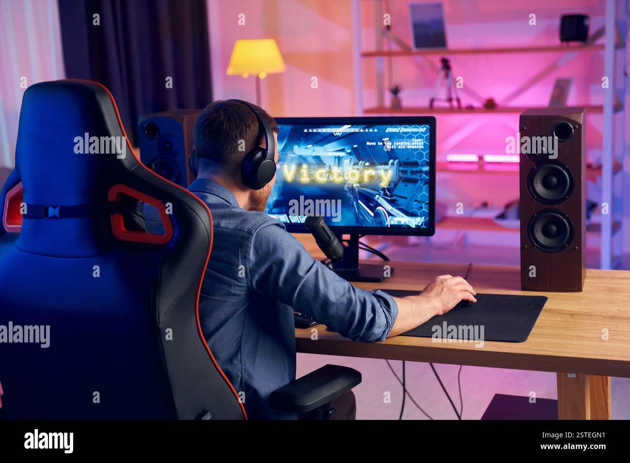 Blick von hinten. Online-Streamer, der FPS-Shooter zu Hause spielt. Stockfoto