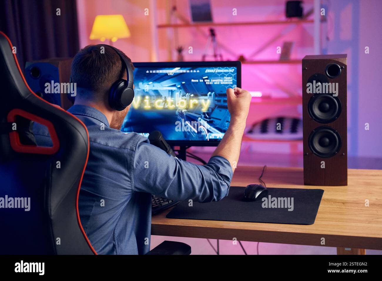 Blick von hinten. Online-Streamer, der FPS-Shooter zu Hause spielt. Stockfoto