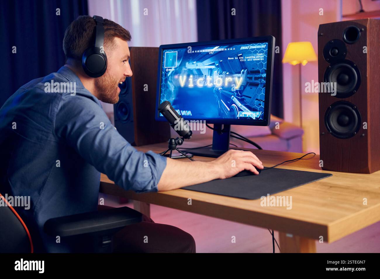 Der Mann gewinnt dieses Spiel. Online-Streamer spielt FPS-Shooter zu Hause. Stockfoto