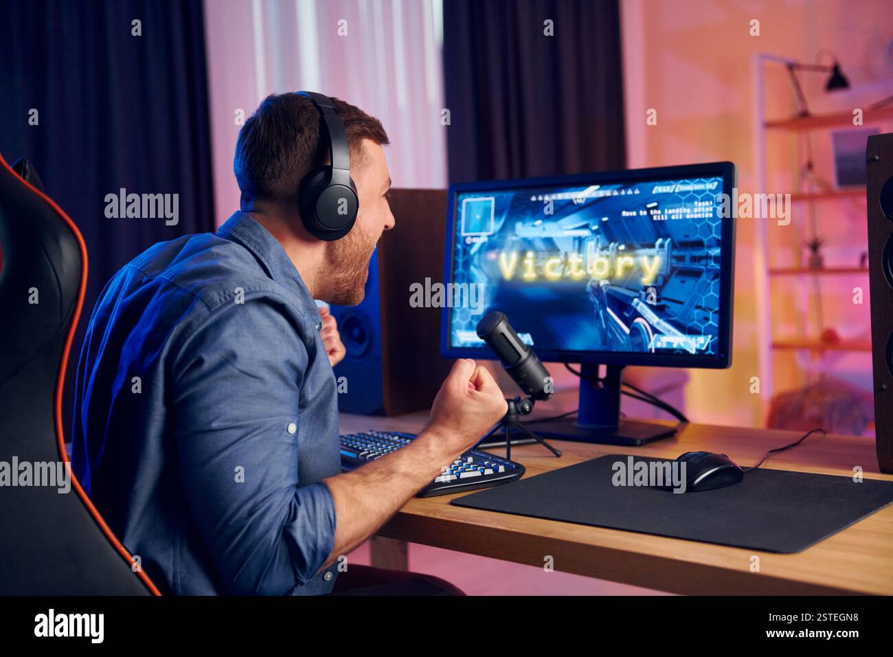 Der Mann gewinnt dieses Spiel. Online-Streamer spielt FPS-Shooter zu Hause. Stockfoto