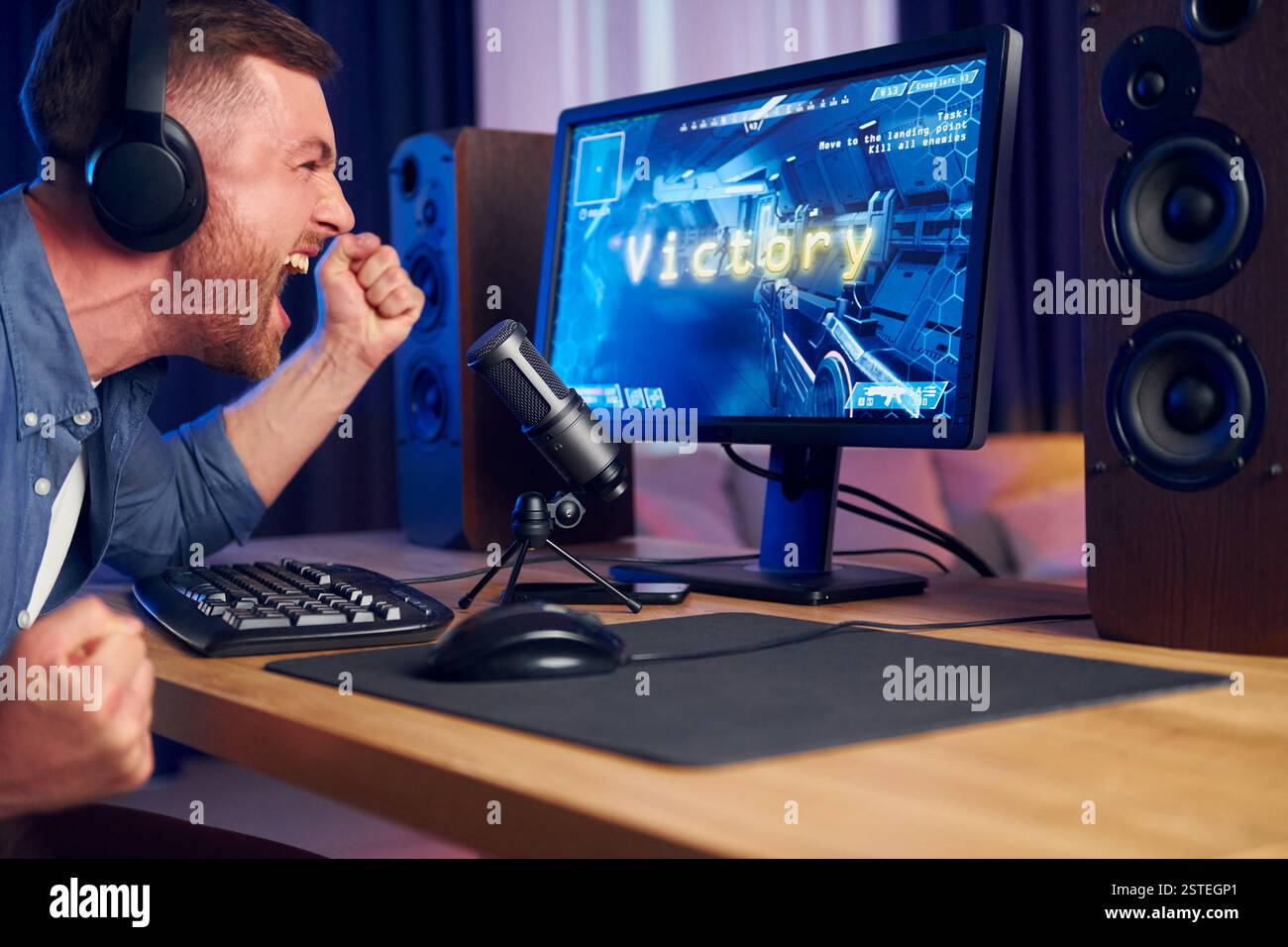 Schreiend und feiert den Sieg. Online-Streamer, der FPS-Shooter zu Hause spielt. Stockfoto