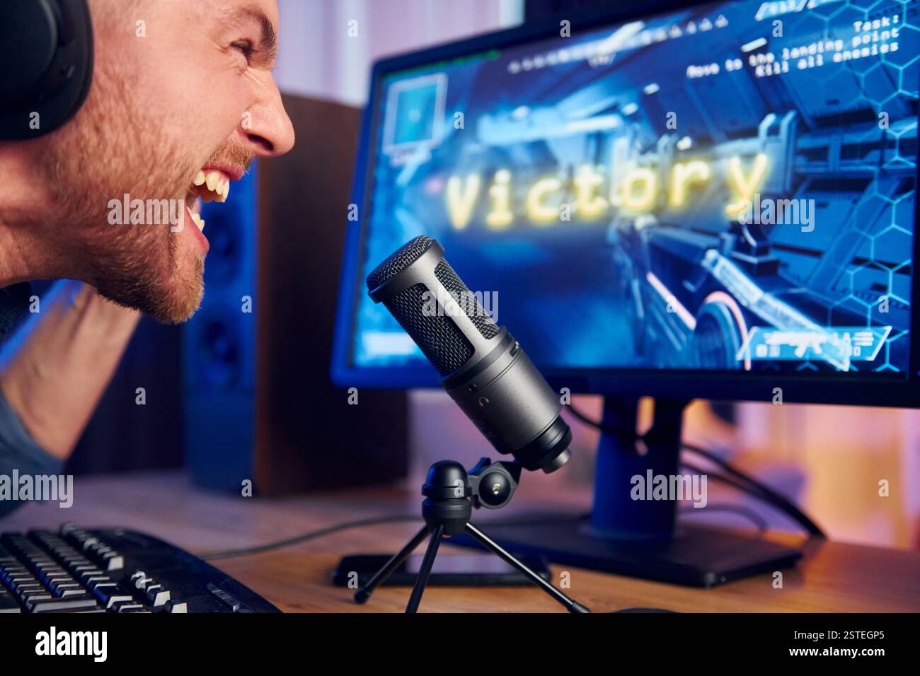 Schreiend und feiert den Sieg. Online-Streamer, der FPS-Shooter zu Hause spielt. Stockfoto