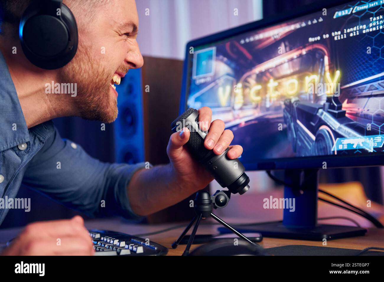 Schreiend und feiert den Sieg. Online-Streamer, der FPS-Shooter zu Hause spielt. Stockfoto