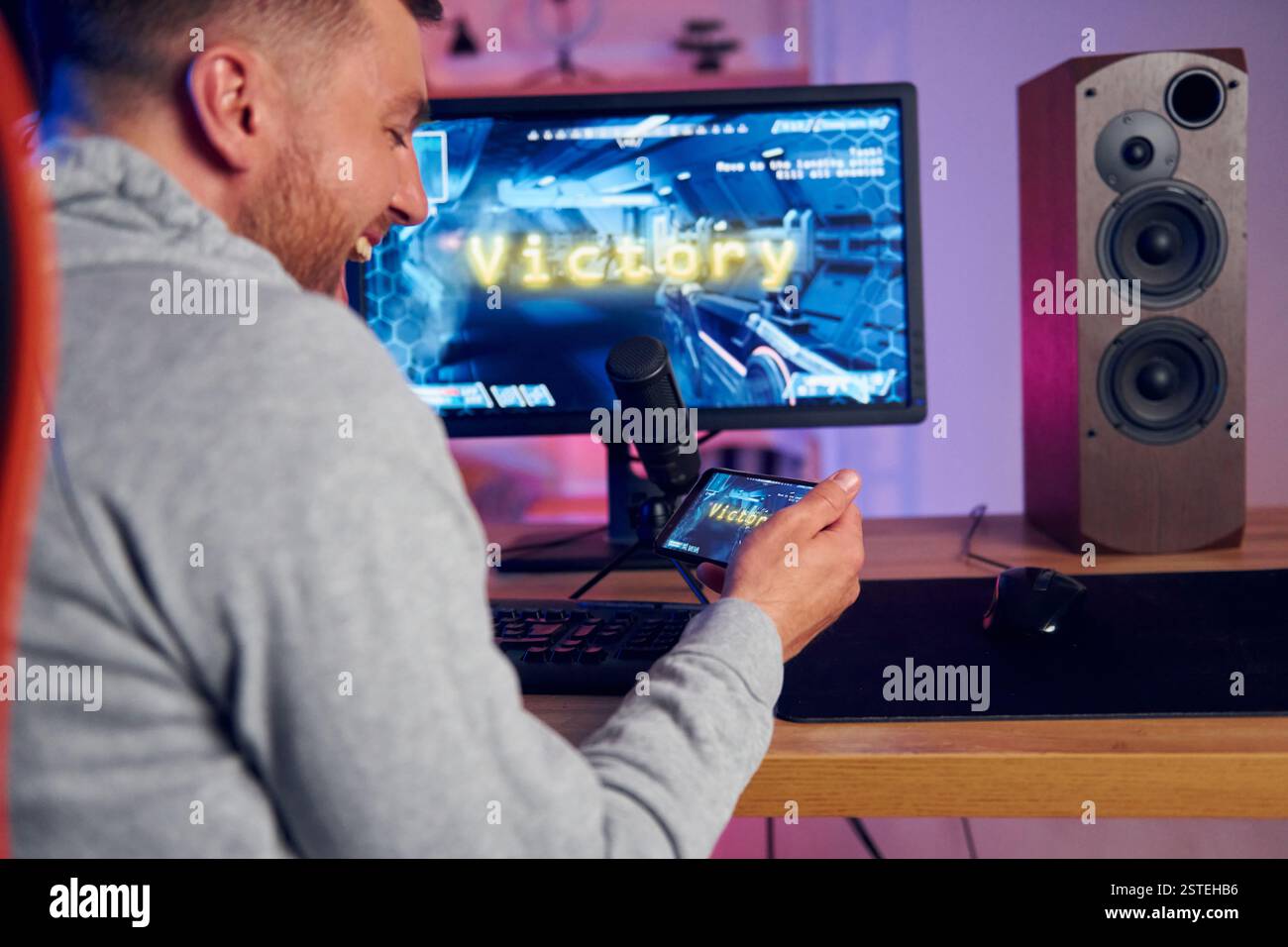 Sieg, glücklicher Mann, der feiert. Online-Streamer, der FPS-Shooter zu Hause spielt. Stockfoto